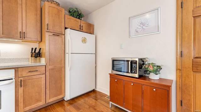 kitchen featuring stove, light hardwood / wood-style floors, and white refrigerator