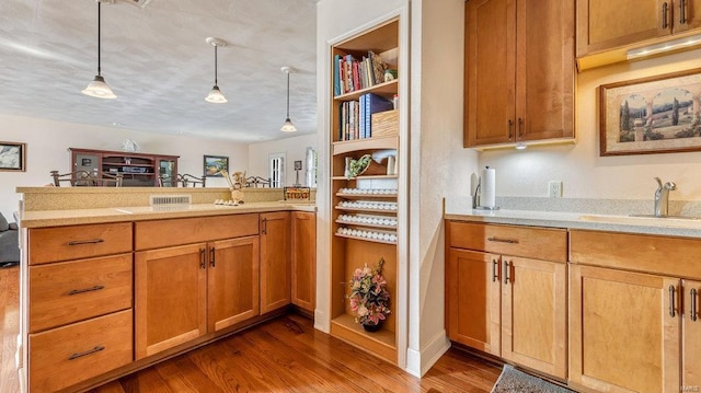 kitchen featuring hanging light fixtures, hardwood / wood-style flooring, sink, and kitchen peninsula