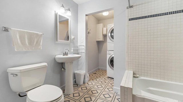 full bathroom with stacked washing maching and dryer, sink, tiled shower / bath, and toilet