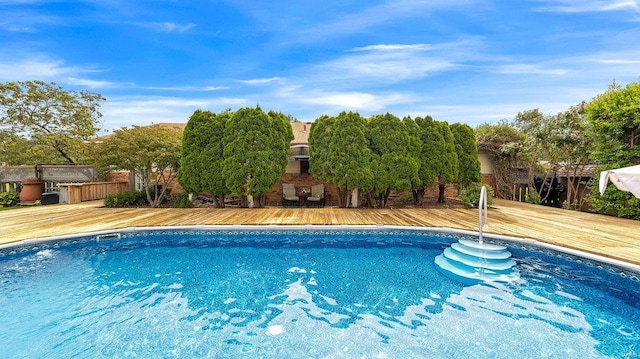 view of swimming pool featuring a deck and an outdoor stone fireplace