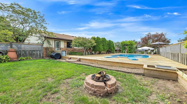 view of pool featuring a wooden deck, an outdoor fire pit, and a yard