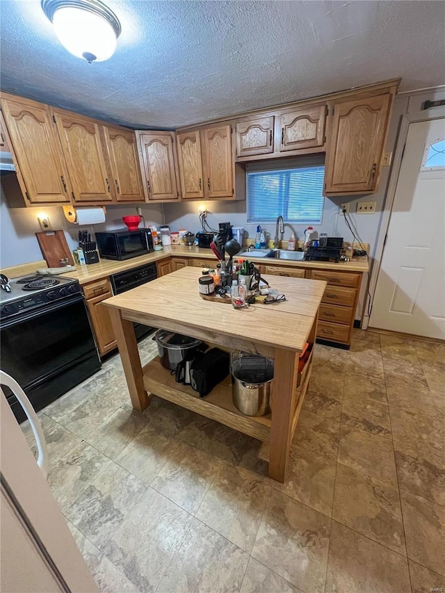 kitchen featuring sink, black appliances, and a textured ceiling