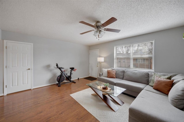 living room with hardwood / wood-style flooring, ceiling fan, and a textured ceiling