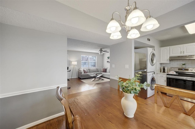 dining room with ceiling fan, stacked washer and clothes dryer, hardwood / wood-style floors, and a textured ceiling