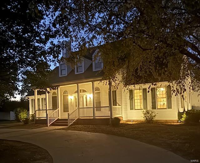 cape cod home featuring a porch