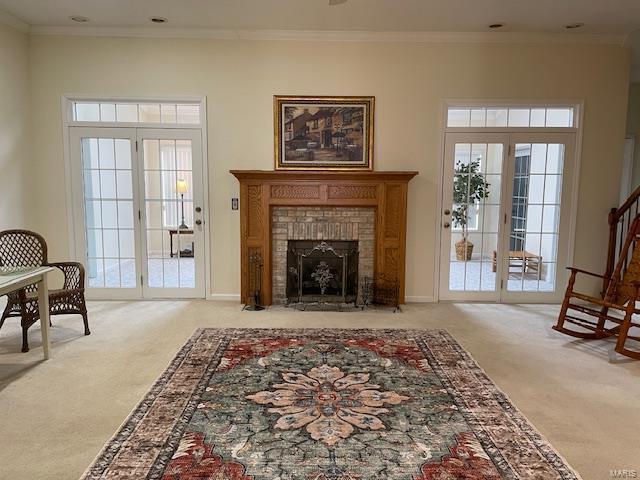 sitting room with crown molding, light carpet, a fireplace, and french doors