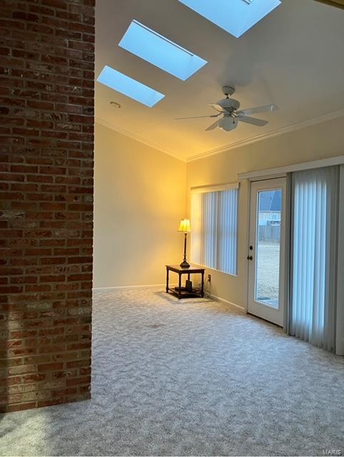 carpeted empty room with lofted ceiling, crown molding, and ceiling fan