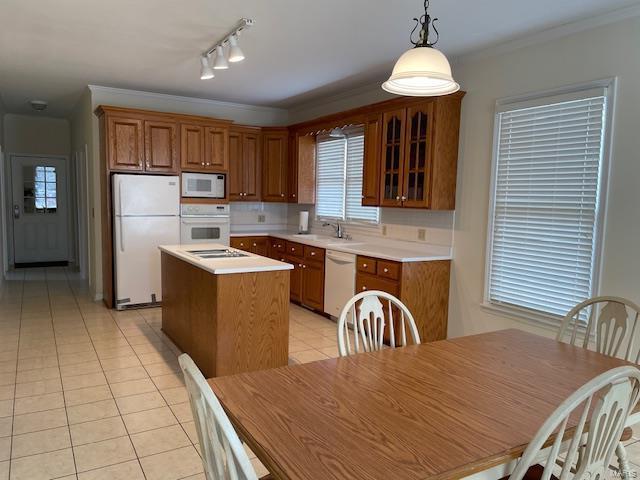 kitchen featuring a kitchen island, decorative light fixtures, ornamental molding, light tile patterned floors, and white appliances