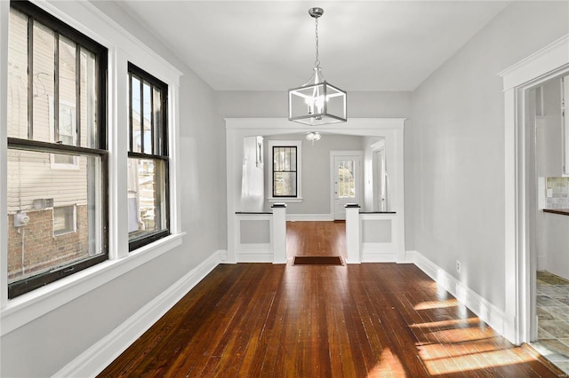 unfurnished dining area featuring dark hardwood / wood-style flooring and a notable chandelier