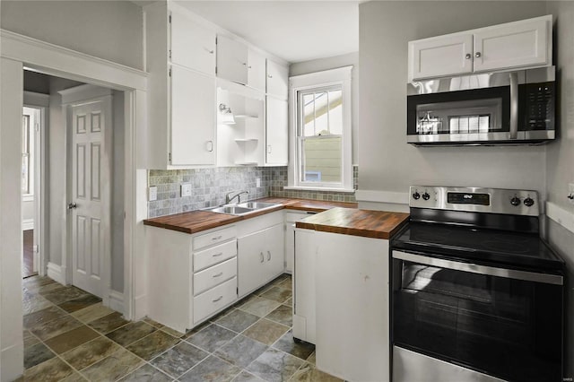 kitchen featuring sink, butcher block countertops, stainless steel appliances, decorative backsplash, and white cabinets