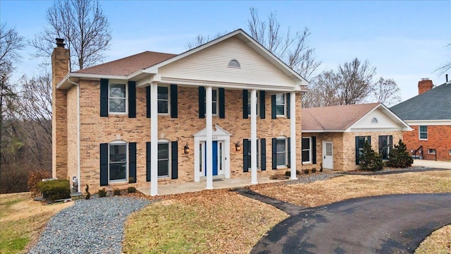 greek revival inspired property featuring brick siding and a chimney