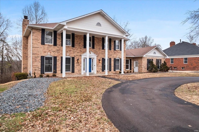 neoclassical home featuring brick siding and a chimney