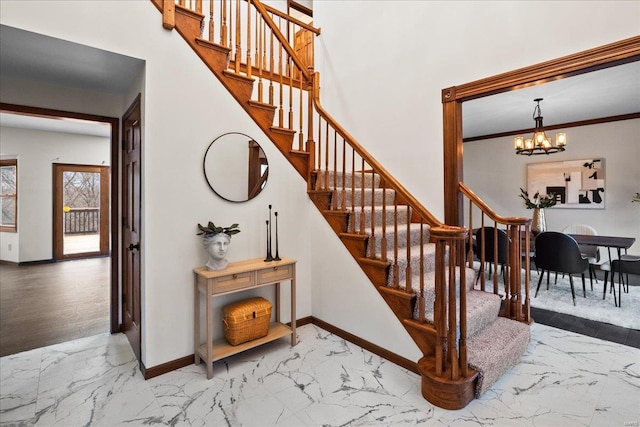 staircase with a notable chandelier, marble finish floor, crown molding, and baseboards