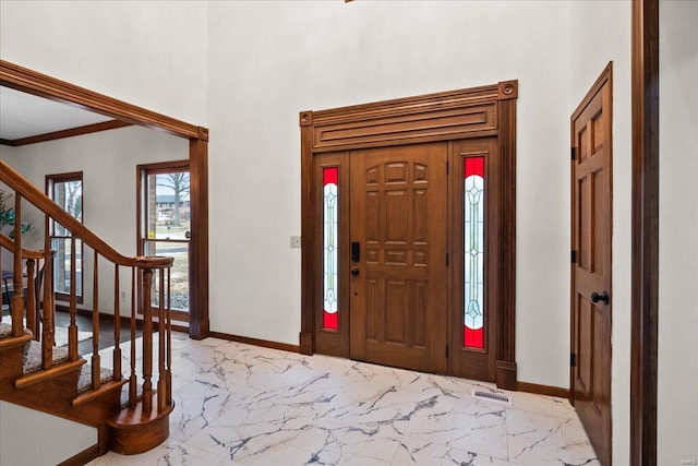 foyer entrance featuring visible vents, marble finish floor, ornamental molding, baseboards, and stairs