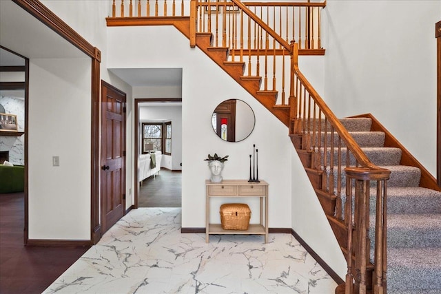 stairs with a towering ceiling, baseboards, and marble finish floor