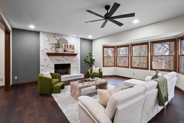 living area with recessed lighting, wood finished floors, baseboards, and a premium fireplace