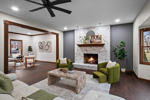 living area with ceiling fan, baseboards, a premium fireplace, recessed lighting, and wood finished floors