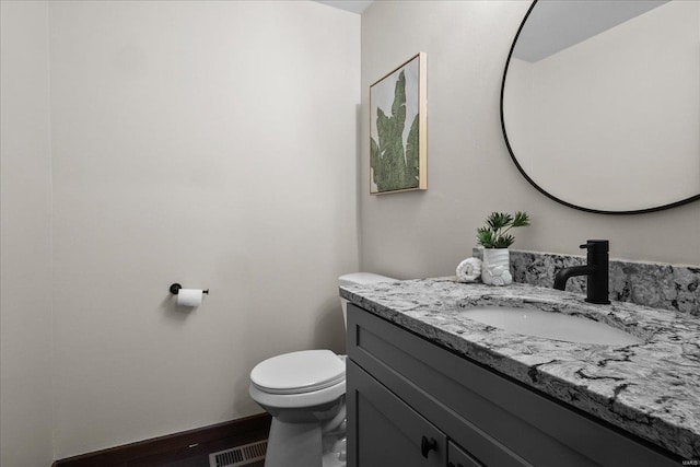 half bathroom with visible vents, toilet, vanity, and baseboards