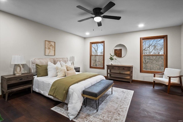 bedroom featuring a ceiling fan, multiple windows, wood finished floors, and baseboards