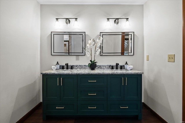 bathroom with a sink, baseboards, and double vanity