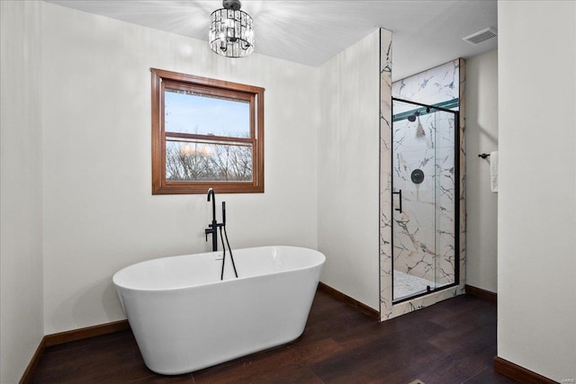 full bathroom featuring a marble finish shower, visible vents, baseboards, a freestanding tub, and wood finished floors