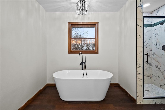 full bathroom with a freestanding tub, a marble finish shower, baseboards, and wood finished floors