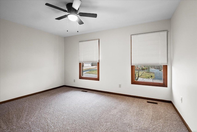 carpeted spare room with visible vents, baseboards, and a ceiling fan