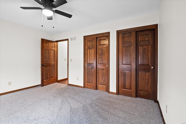 unfurnished bedroom featuring visible vents, two closets, a ceiling fan, carpet, and baseboards