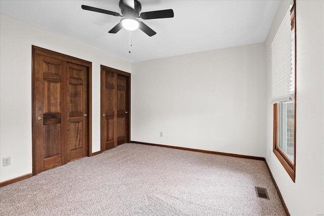 unfurnished bedroom with visible vents, baseboards, multiple closets, and carpet floors