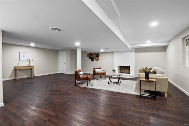 living area featuring visible vents, a fireplace, baseboards, and wood finished floors