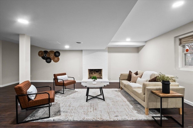 living room featuring a large fireplace, baseboards, and wood finished floors