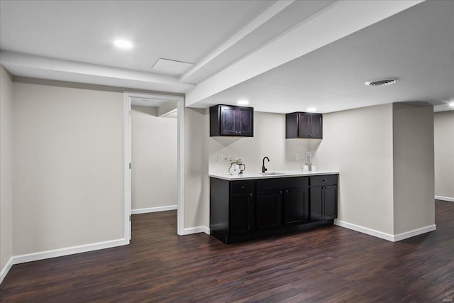 bar with dark wood-style floors, visible vents, baseboards, wet bar, and a sink