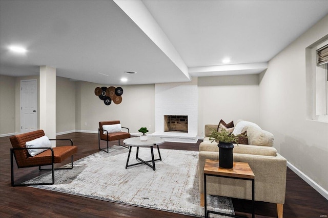 living room featuring a brick fireplace, baseboards, and wood finished floors