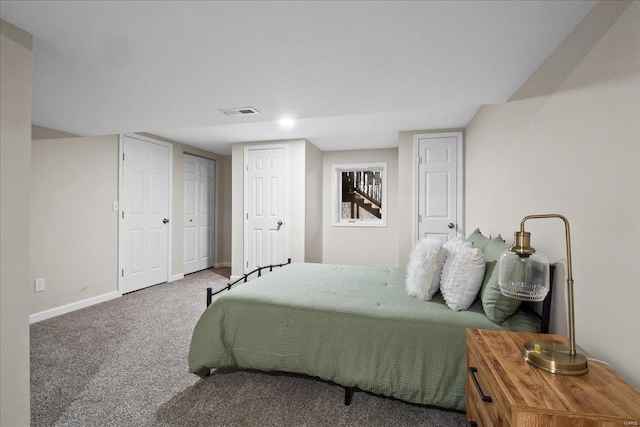 bedroom featuring carpet flooring, visible vents, baseboards, and multiple closets