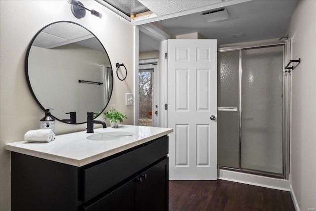 full bathroom with visible vents, vanity, wood finished floors, and a shower stall