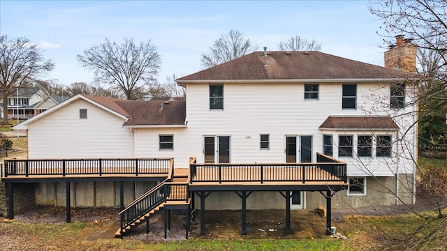 rear view of house with a chimney, stairs, a deck, and roof with shingles