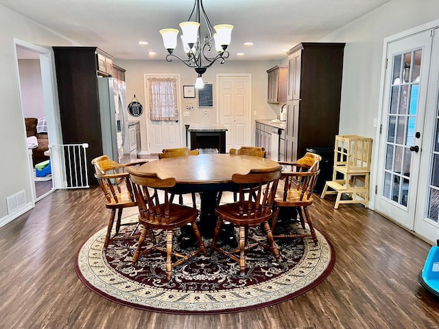 dining space with dark hardwood / wood-style floors, a chandelier, and french doors