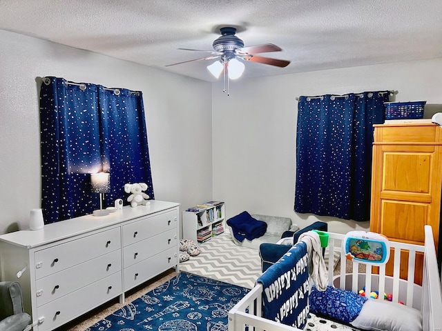 bedroom featuring a crib, carpet, a textured ceiling, and ceiling fan