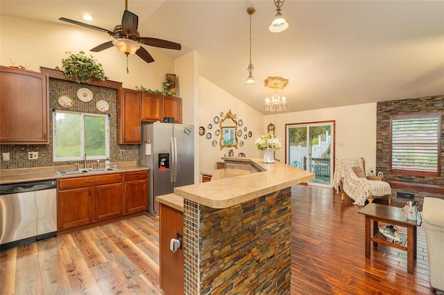 kitchen featuring stainless steel appliances, hanging light fixtures, sink, and lofted ceiling