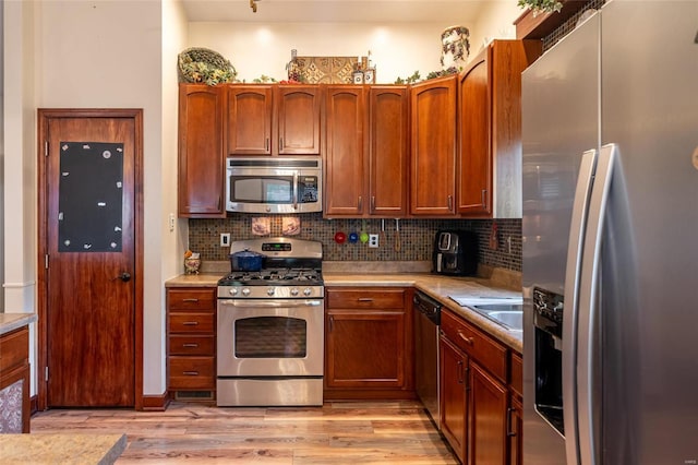 kitchen featuring stainless steel appliances, sink, light hardwood / wood-style floors, and decorative backsplash