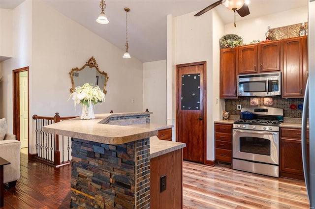 kitchen featuring stainless steel appliances, tasteful backsplash, hanging light fixtures, and light hardwood / wood-style flooring