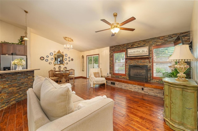 living room featuring lofted ceiling, dark wood-type flooring, ceiling fan with notable chandelier, and a fireplace