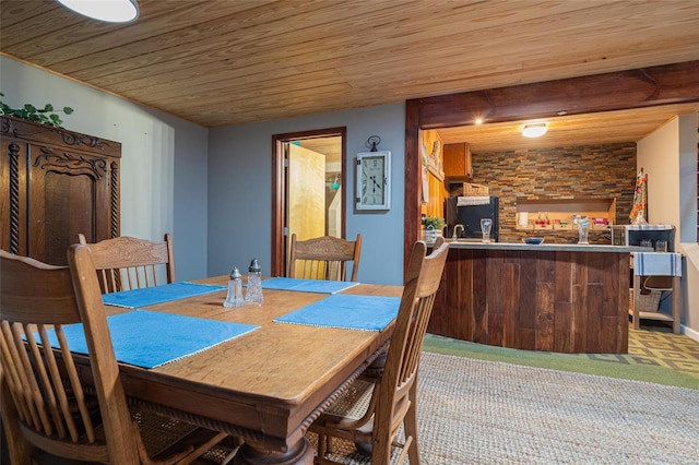 carpeted dining space featuring bar and wooden ceiling