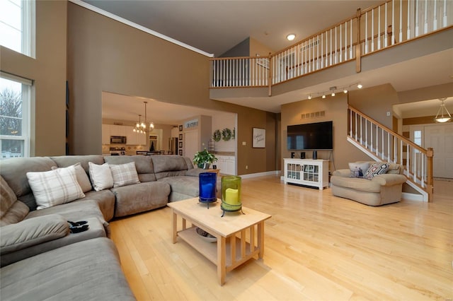 living room with a high ceiling, an inviting chandelier, and light hardwood / wood-style flooring