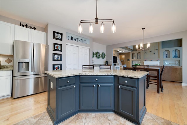 kitchen featuring stainless steel fridge, a center island, white cabinets, decorative light fixtures, and a chandelier