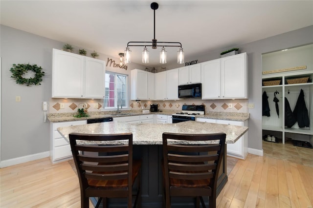 kitchen with white cabinetry, a center island, range with gas stovetop, and sink