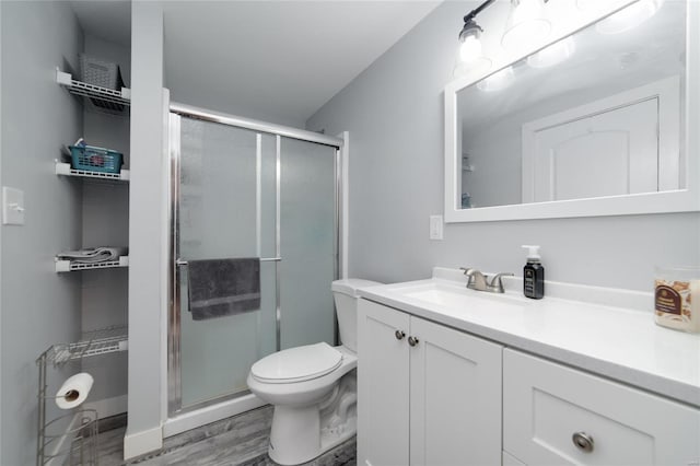 bathroom featuring vanity, wood-type flooring, walk in shower, and toilet