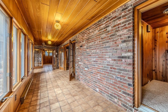 corridor featuring wood ceiling and brick wall