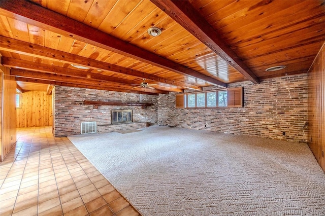 unfurnished living room featuring brick wall, light tile patterned flooring, a brick fireplace, wooden ceiling, and beamed ceiling