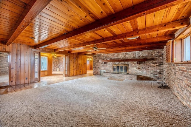 unfurnished living room featuring beam ceiling, brick wall, and a fireplace